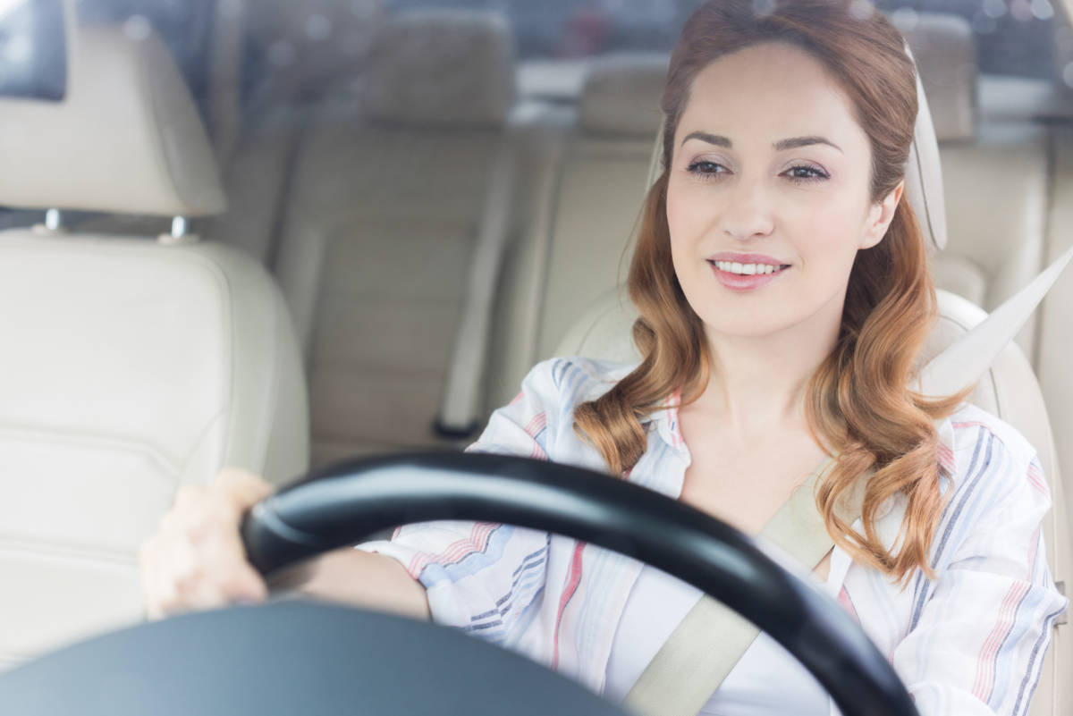 portrait of smiling woman driving car alone